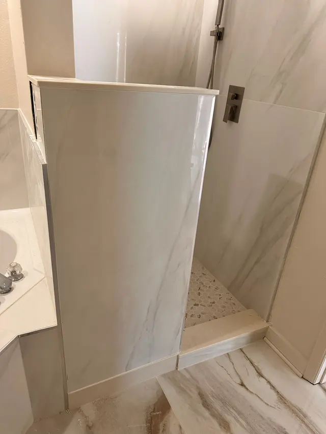 Walk in shower with a glass panel and light tile walls