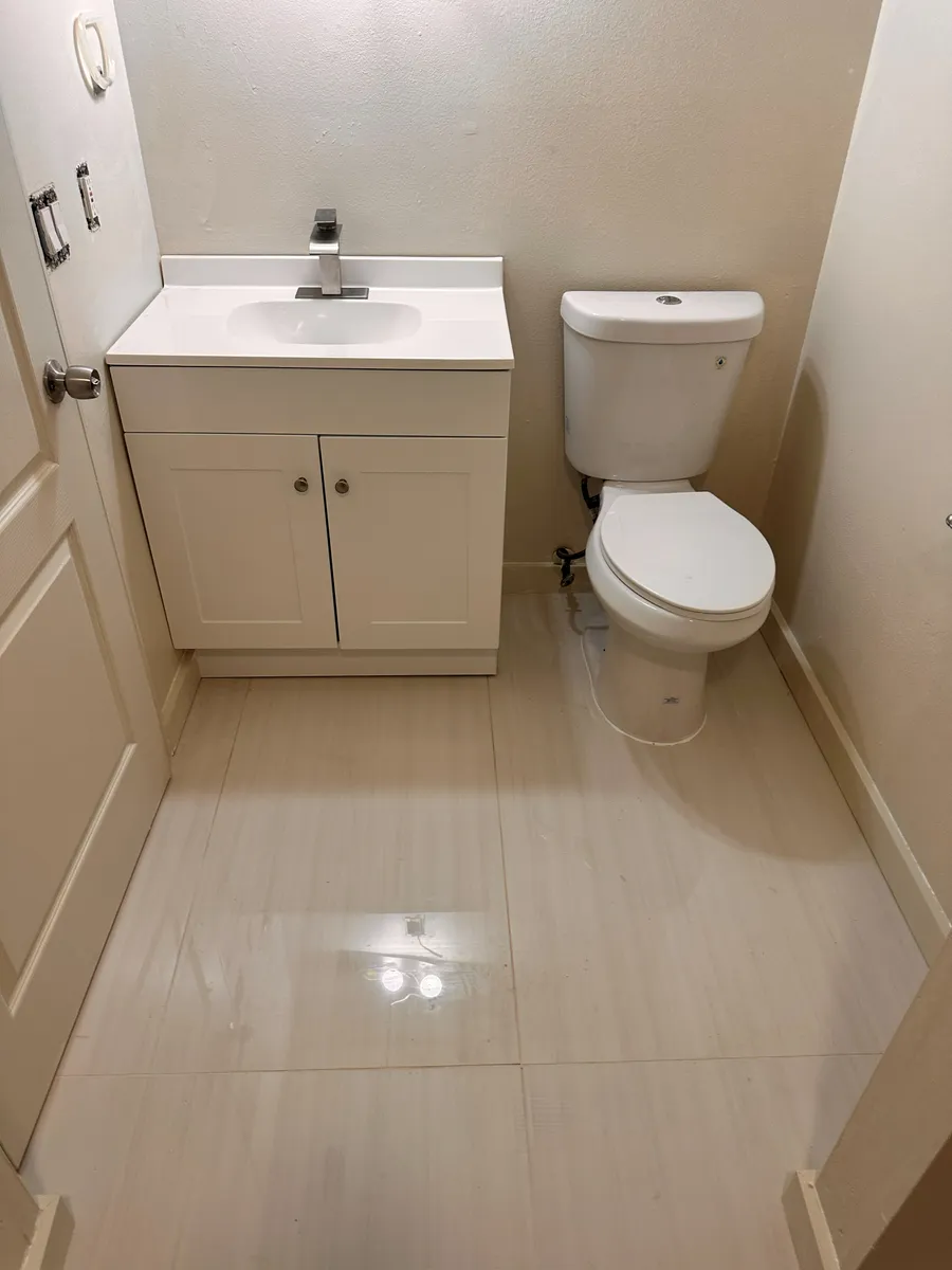Bathroom finished by B2B Construction with a white vanity, a toilet and large format tile flooring